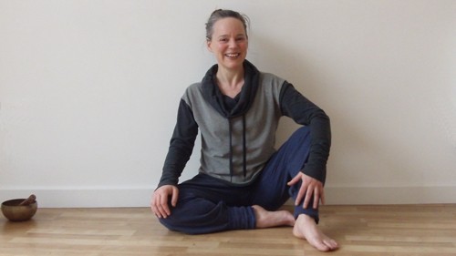 Spike Warwick sitting cross-legged on the wooden floor of the practice room, smiling
